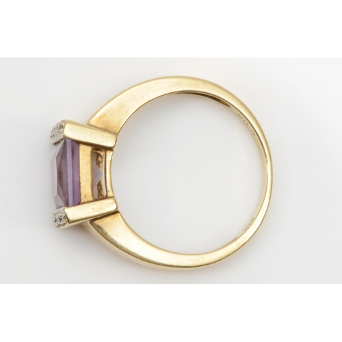 103 - A 9ct gold princess cut amethyst dress ring, the amethyst flanked by diamonds, P, 3.8gm.