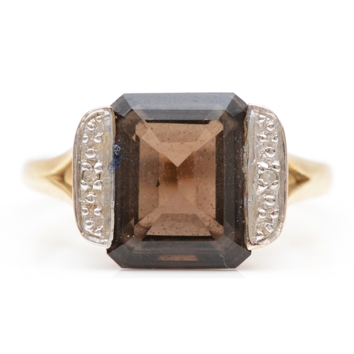 104 - A 9ct gold emerald cut smokey quartz dress ring, the quartz flanked by two illusion set diamonds, P,... 