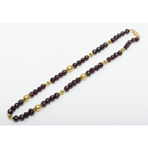 140 - A 14k gold clasped garnet and peridot beaded necklace, 7 - 5mm beads, 39.5gm.