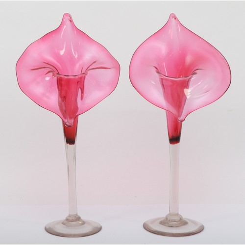 272 - A pair of early 20th cranberry and clear glass Jack in the Pulpit style vases, each raised on circul... 