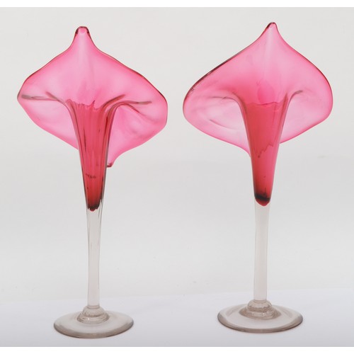 272 - A pair of early 20th cranberry and clear glass Jack in the Pulpit style vases, each raised on circul... 