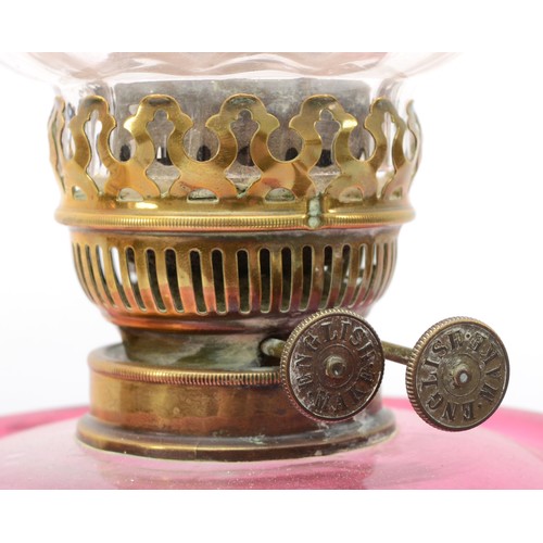 256 - A 19th/early 20th century brass and glass oil lamp, with clear and cranberry glass shade etched with... 