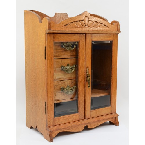 258 - An early 20th century golden oak twin glass door table top smokers cabinet, opening to reveal pipe s... 