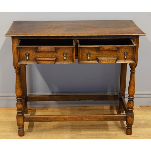 442 - An early 20th century oak Jacobean style twin panelled drawer low boy, each with brass drop handles ... 