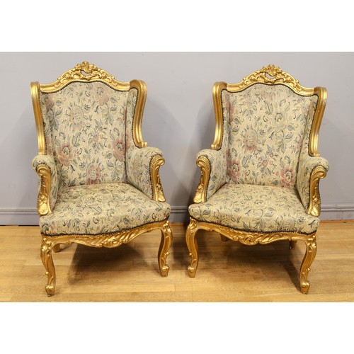 448 - A pair of early 20th century gilt framed wing back arm chairs, raised on carved cabriole supports te... 