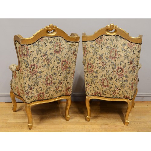 448 - A pair of early 20th century gilt framed wing back arm chairs, raised on carved cabriole supports te... 