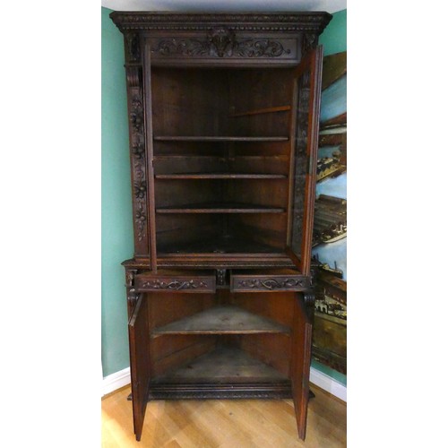 457 - A 19th century heavily carved oak corner cupboard, with two glass doors opening to reveal three adju... 