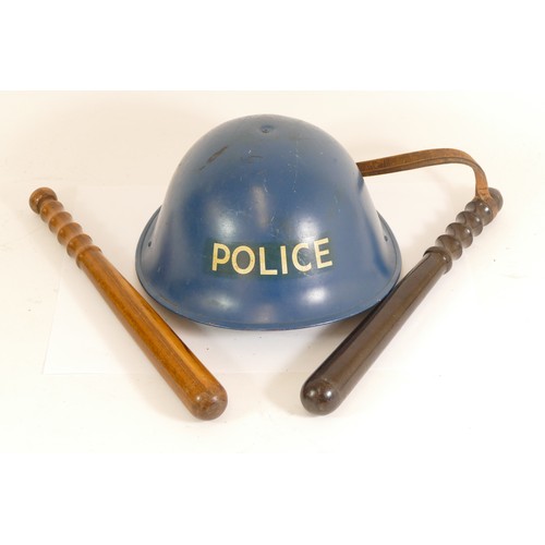 559 - A blue painted turtle helmet marked Police and two wooden truncheons