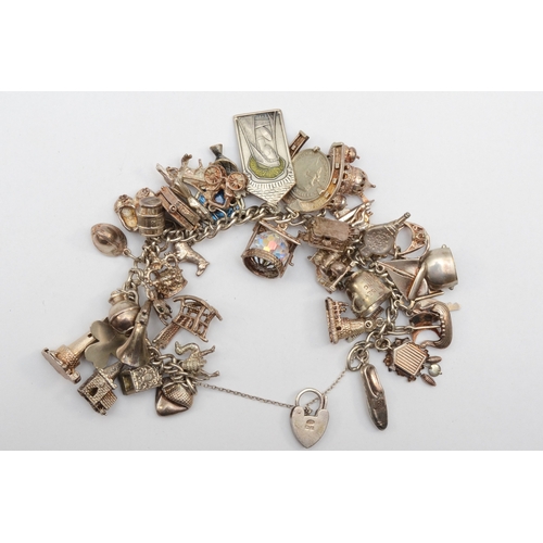 159 - A silver heart shaped clasped charm bracelet with religious charms, 107gm.