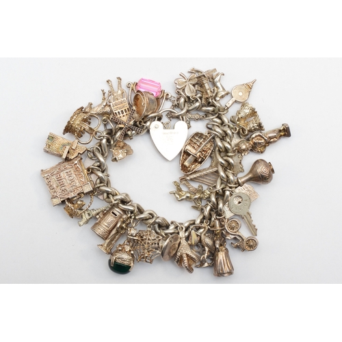 184 - A heavy silver heart shaped clasped charm bracelet, 143gm.