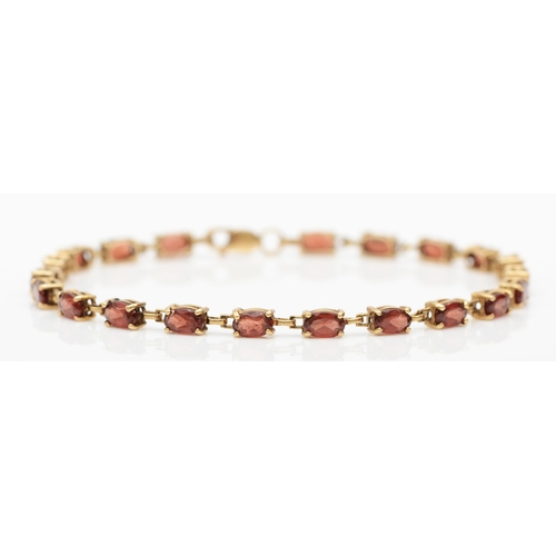 229 - A 10k gold garnet tennis bracelet, 18cm, 4.6gm.