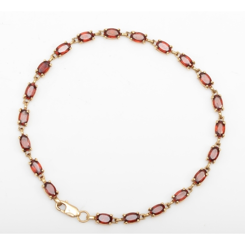 229 - A 10k gold garnet tennis bracelet, 18cm, 4.6gm.