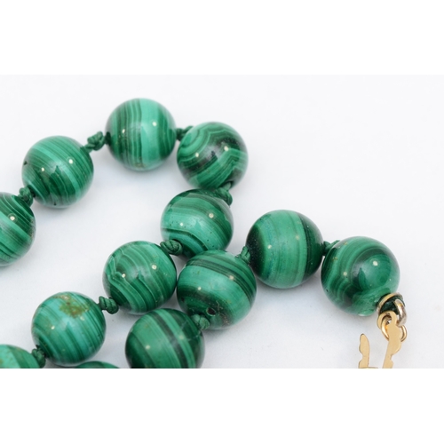 375 - A 14k gold clasped malachite beaded necklace, 7mm beads, 72cm, 66.9gm.