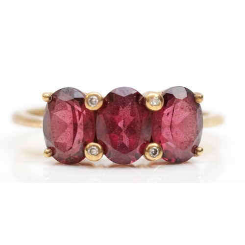 383 - A 9ct gold three stone garnet dress ring, O, 2.5gm.