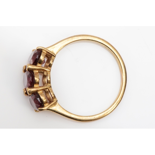 383 - A 9ct gold three stone garnet dress ring, O, 2.5gm.