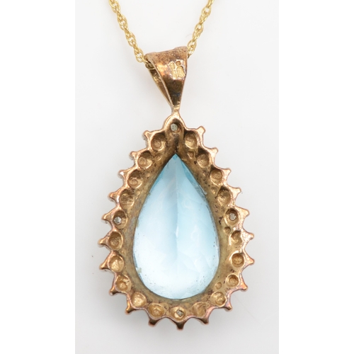 404 - A 9ct gold pear cut blue topaz and diamond cluster pendant, on chain, 24 x 13mm, 3.3gm.