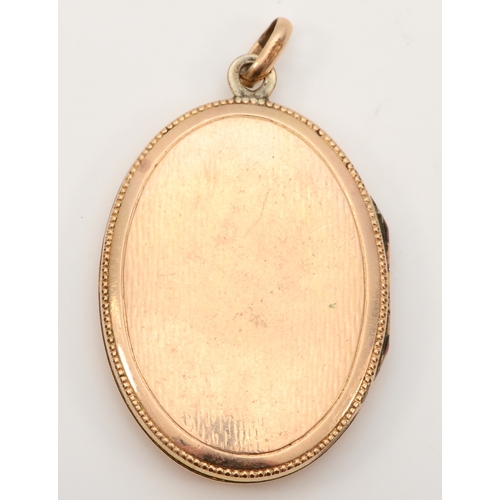 432 - An unmarked gold front and backed oval locket, with red paste stone and chased floral decoration, 40... 