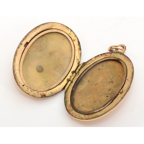 432 - An unmarked gold front and backed oval locket, with red paste stone and chased floral decoration, 40... 