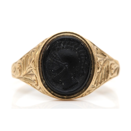 491 - A 9ct gold jet signet ring, with carved legionary bust, U, 2.5gm.