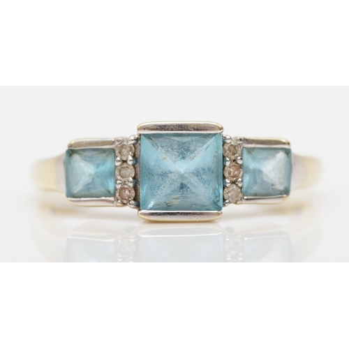 499 - A 9ct white gold three stone blue topaz dress ring, spaced with diamonds, K, 1.7gm.