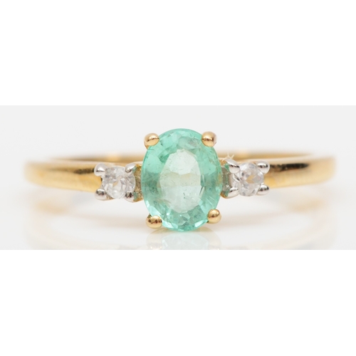 567 - A 9ct gold emerald dress ring, flanked by two brilliant cut diamonds, M, 1.6gm.