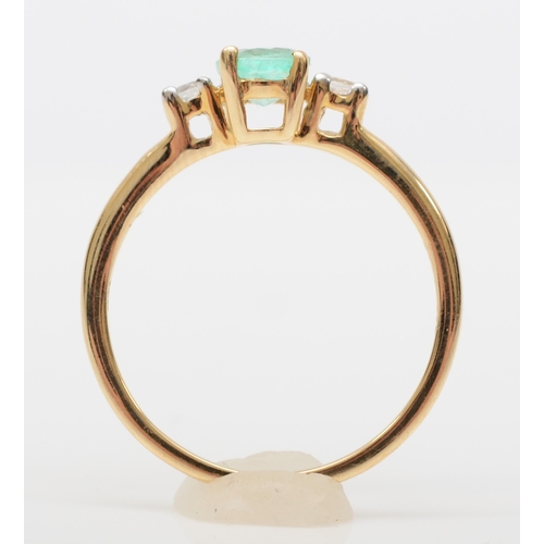 567 - A 9ct gold emerald dress ring, flanked by two brilliant cut diamonds, M, 1.6gm.