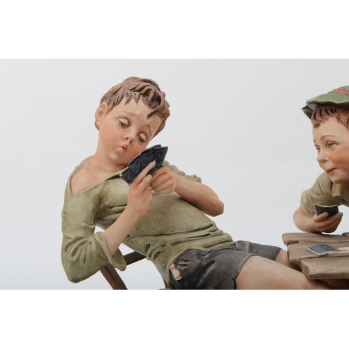 150 - A 20th century Capodimonte porcelain figure, The Cheats, modelled by B.Merli, raised on an oval wood... 