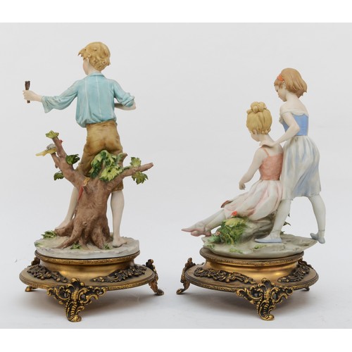 162 - Two 20th century Capodimonte painted porcelain figures, two females reading a book and a boy with a ... 