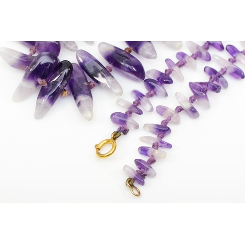 204 - A 9k gold clasped graduated tumbled amethyst necklace, 91cm, together with a similar necklace.