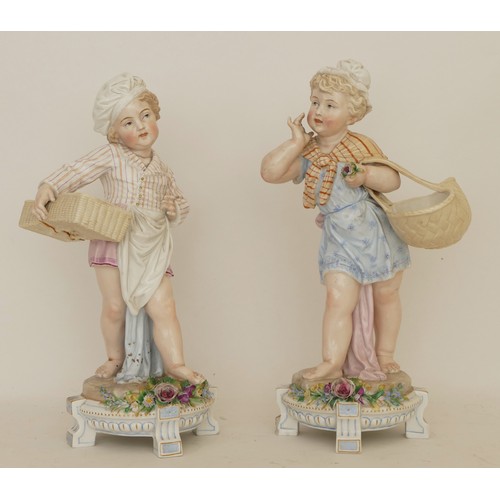 66 - A pair of 20th century porcelain figures, boy and girl each carrying a basket, raised on four suppor... 