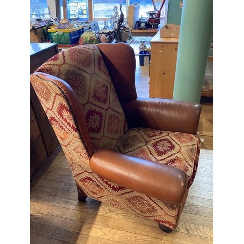 A large modern wingback armchair, upholstered in tan leather and patterned chenille fabric, with feather filled removable cushioned seat, raised on turned supports, W94, H108cm.