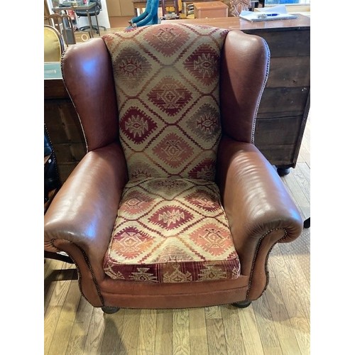 279 - A large modern wingback armchair, upholstered in tan leather and patterned chenille fabric, with fea... 