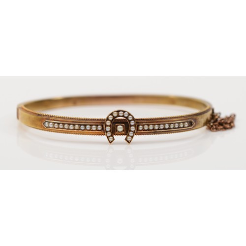 123 - A Victorian 15ct gold horseshoe bangle, set with seed pearls, bead border and safety chain, 59mm, 8.... 