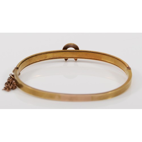 123 - A Victorian 15ct gold horseshoe bangle, set with seed pearls, bead border and safety chain, 59mm, 8.... 