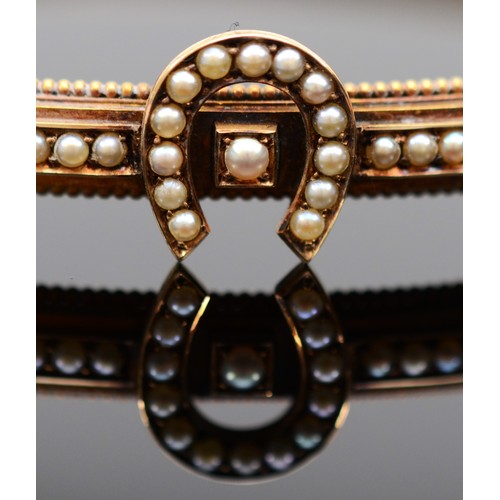 123 - A Victorian 15ct gold horseshoe bangle, set with seed pearls, bead border and safety chain, 59mm, 8.... 