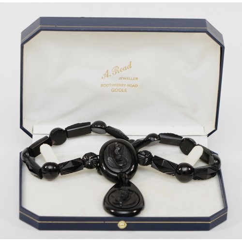 127 - A Victorian Whitby jet and silver clasped necklace, with carved floral pendant and spacers, 44cm, re... 