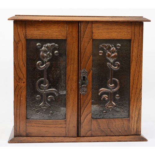 238 - An Arts and Crafts oak and hammered copper twin door smokers cabinet, the panels decorated with styl... 