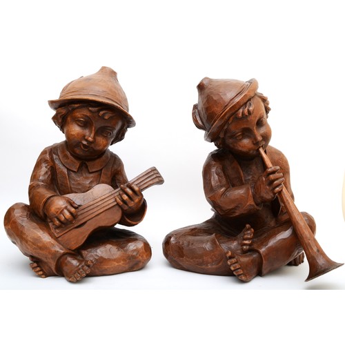 244 - A rare pair of carved wood Hummel figures, presumed ex shop display, of seated boys playing musical ... 