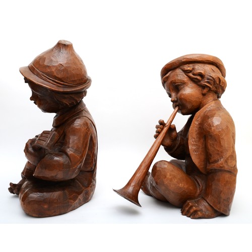 244 - A rare pair of carved wood Hummel figures, presumed ex shop display, of seated boys playing musical ... 