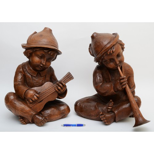 244 - A rare pair of carved wood Hummel figures, presumed ex shop display, of seated boys playing musical ... 