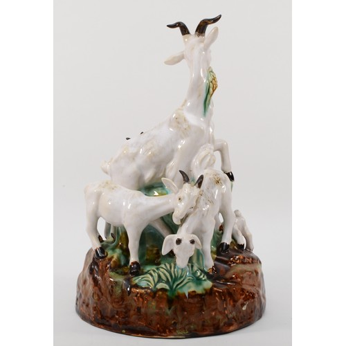 261 - A richly painted and glazed porcelain figural group of four goats raised on naturalistic base, unsig... 