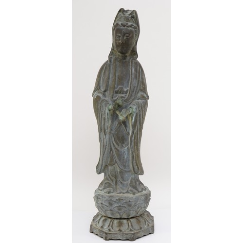 282 - A Chinese bronze figure of Guan Yin holding a scroll weight, standing on a lotus leaf, with incised ... 