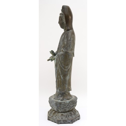 282 - A Chinese bronze figure of Guan Yin holding a scroll weight, standing on a lotus leaf, with incised ... 