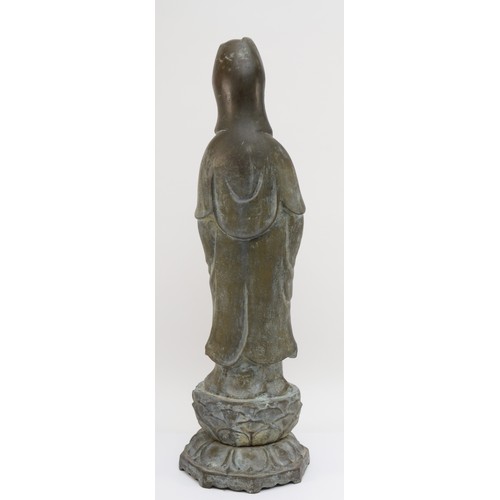 282 - A Chinese bronze figure of Guan Yin holding a scroll weight, standing on a lotus leaf, with incised ... 