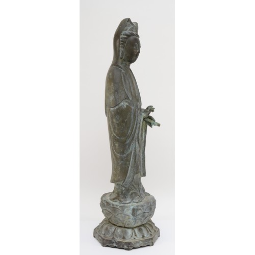 282 - A Chinese bronze figure of Guan Yin holding a scroll weight, standing on a lotus leaf, with incised ... 