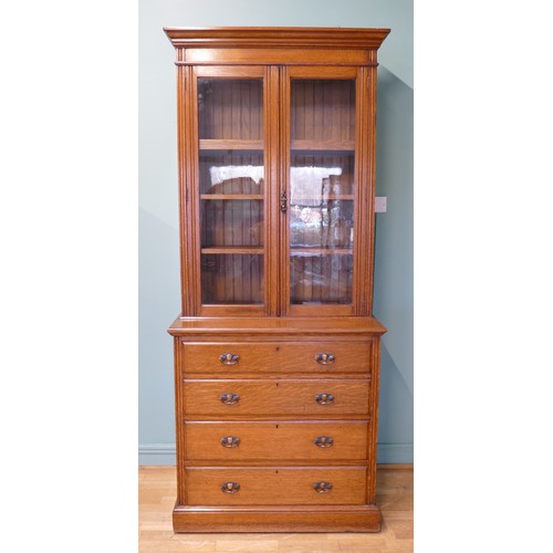 383 - An Edwardian oak twin door glazed bookcase, opening to reveal adjustable shelves above a chest of fo... 