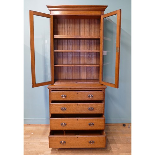 383 - An Edwardian oak twin door glazed bookcase, opening to reveal adjustable shelves above a chest of fo... 