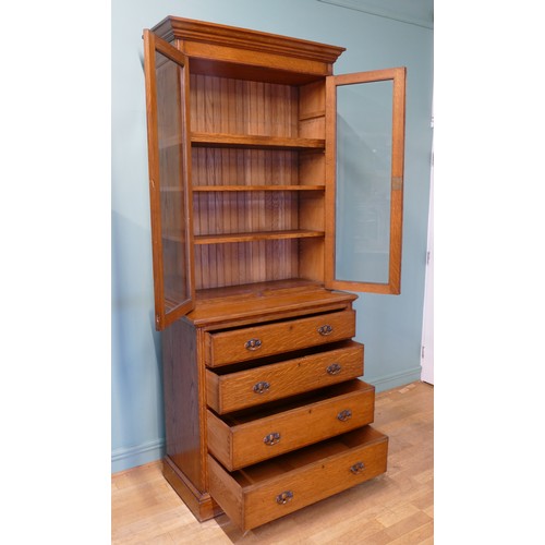 383 - An Edwardian oak twin door glazed bookcase, opening to reveal adjustable shelves above a chest of fo... 