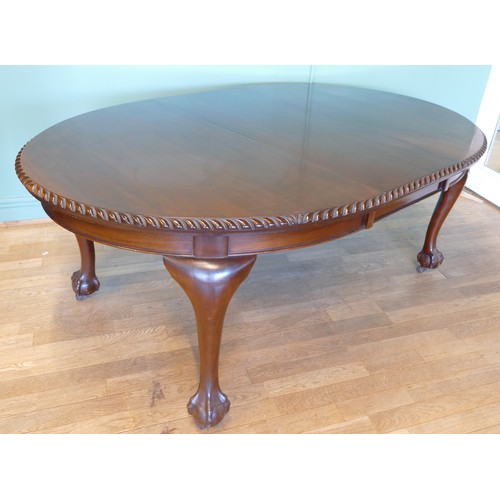 384 - An early 20th century mahogany wind out extending dining table with carved moulding, raised on cabri... 