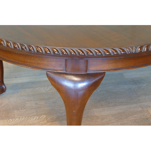 384 - An early 20th century mahogany wind out extending dining table with carved moulding, raised on cabri... 